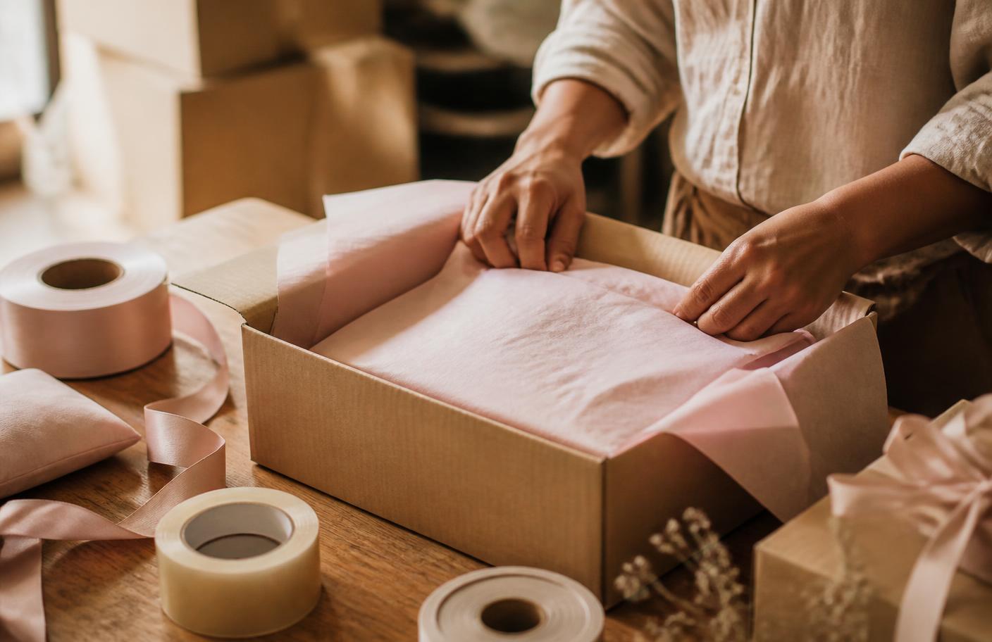 Branded tissue paper, tape and packing supplies on the Pretty Packed Box packing table